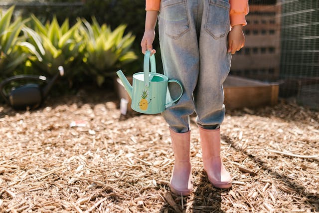 close-up-photo-of-child-wearing-pink-boots-and-carrying-water-sprinkler